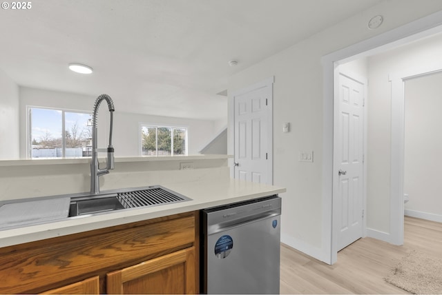 kitchen with light wood-style flooring, baseboards, light countertops, dishwasher, and brown cabinetry