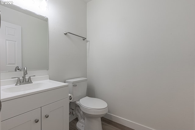 bathroom with wood finished floors, vanity, toilet, and baseboards