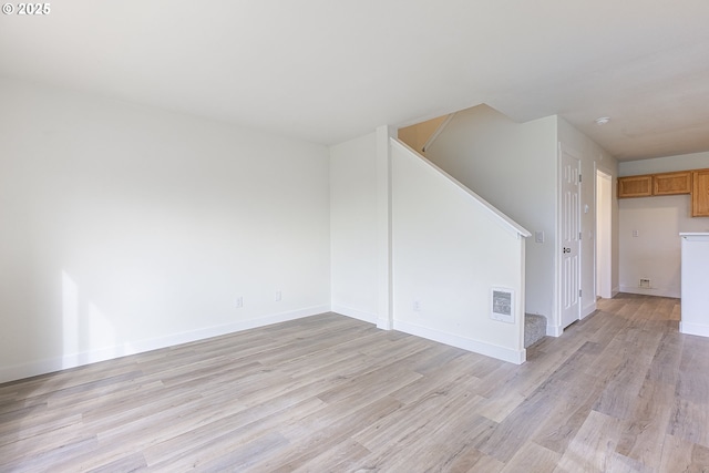 unfurnished living room with baseboards, visible vents, light wood finished floors, and stairs