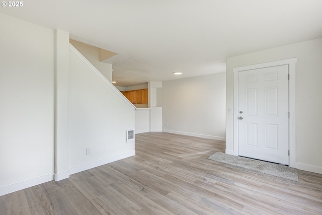 unfurnished room featuring light wood-type flooring, baseboards, stairs, and visible vents