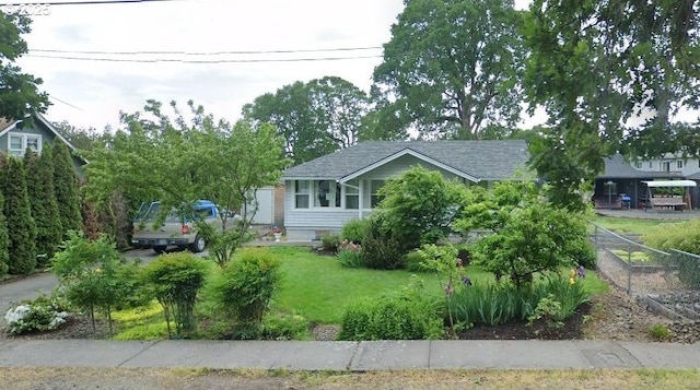 view of home's exterior featuring a lawn, fence, and roof with shingles