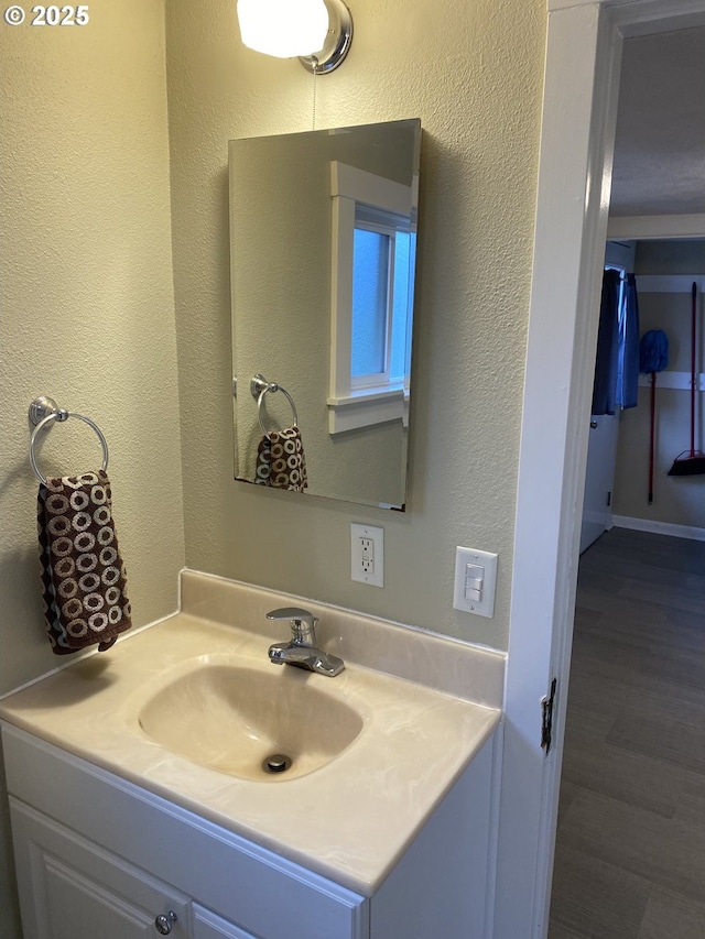 bathroom featuring wood finished floors, vanity, and a textured wall