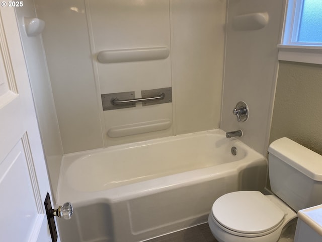 bathroom with shower / bathing tub combination, toilet, and a textured wall