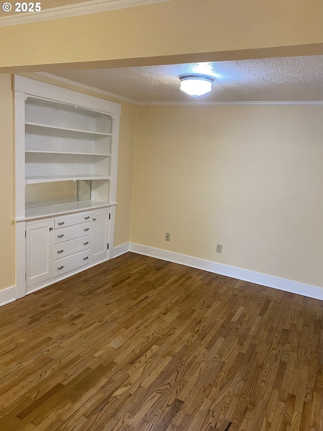 empty room with dark wood-style floors, a textured ceiling, baseboards, and ornamental molding