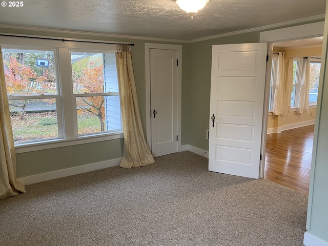 unfurnished room with crown molding, baseboards, carpet floors, and a textured ceiling