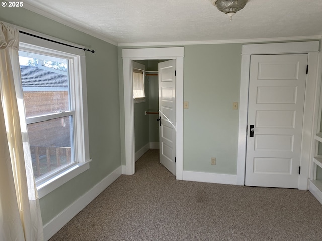 unfurnished bedroom with carpet, baseboards, ornamental molding, a closet, and a textured ceiling