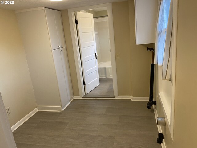 hallway featuring dark wood finished floors and baseboards