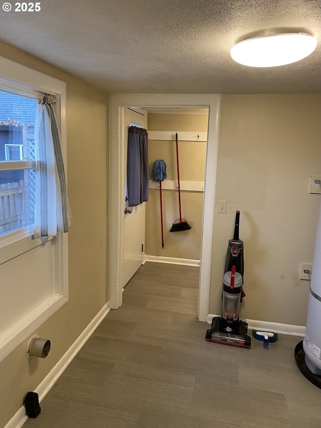 hallway with dark wood finished floors, a textured ceiling, and baseboards