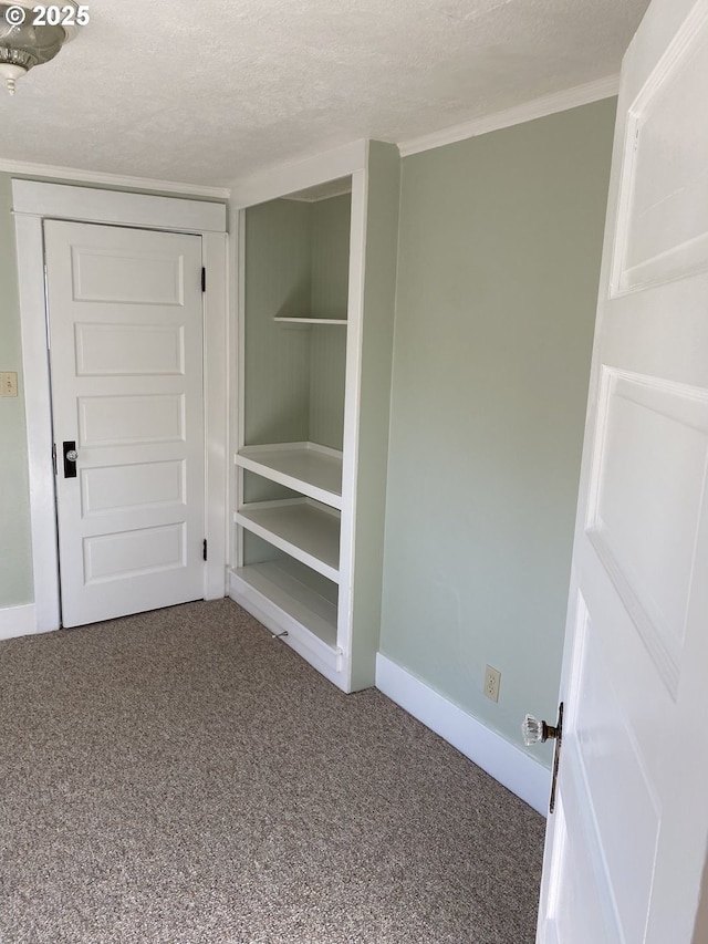 interior space with a closet, a textured ceiling, baseboards, and carpet floors