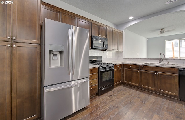 kitchen featuring black appliances, a sink, a textured ceiling, dark wood finished floors, and decorative backsplash