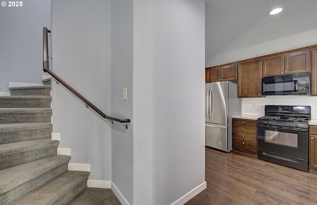 kitchen with baseboards, light countertops, decorative backsplash, black appliances, and dark wood-style flooring