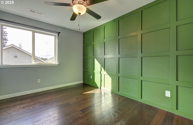 unfurnished bedroom with dark wood-type flooring, a decorative wall, baseboards, and visible vents