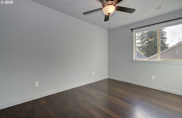 empty room featuring visible vents, baseboards, and dark wood-style flooring