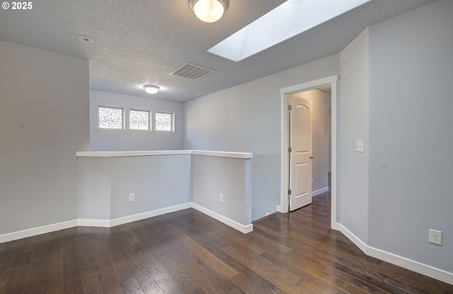 spare room with hardwood / wood-style flooring, baseboards, visible vents, and a textured ceiling