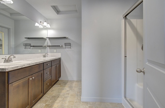 bathroom with double vanity, walk in shower, baseboards, and a sink