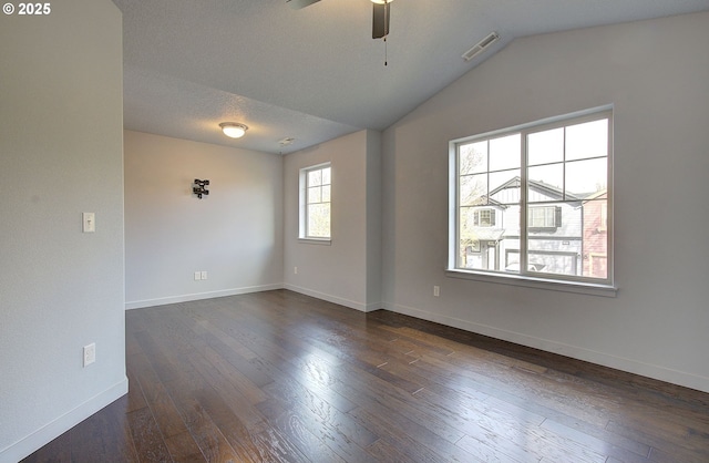 spare room featuring visible vents, baseboards, dark wood finished floors, vaulted ceiling, and a ceiling fan