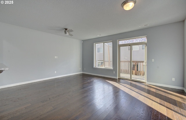 unfurnished room with visible vents, baseboards, ceiling fan, dark wood-type flooring, and a textured ceiling