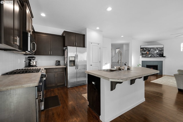 kitchen with sink, stainless steel appliances, a center island with sink, and dark hardwood / wood-style floors