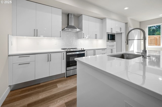 15179 SW Huntwood St, Tigard, OR 97224 - kitchen with appliances with stainless steel finishes, wall chimney range hood, modern cabinets, dark wood-type flooring, and recessed lighting