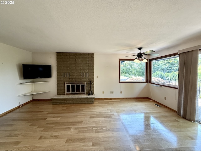 5235 SE 32nd Ave, Portland, OR 97202 - unfurnished living room with a textured ceiling, a ceiling fan, a brick fireplace, and light wood-style flooring