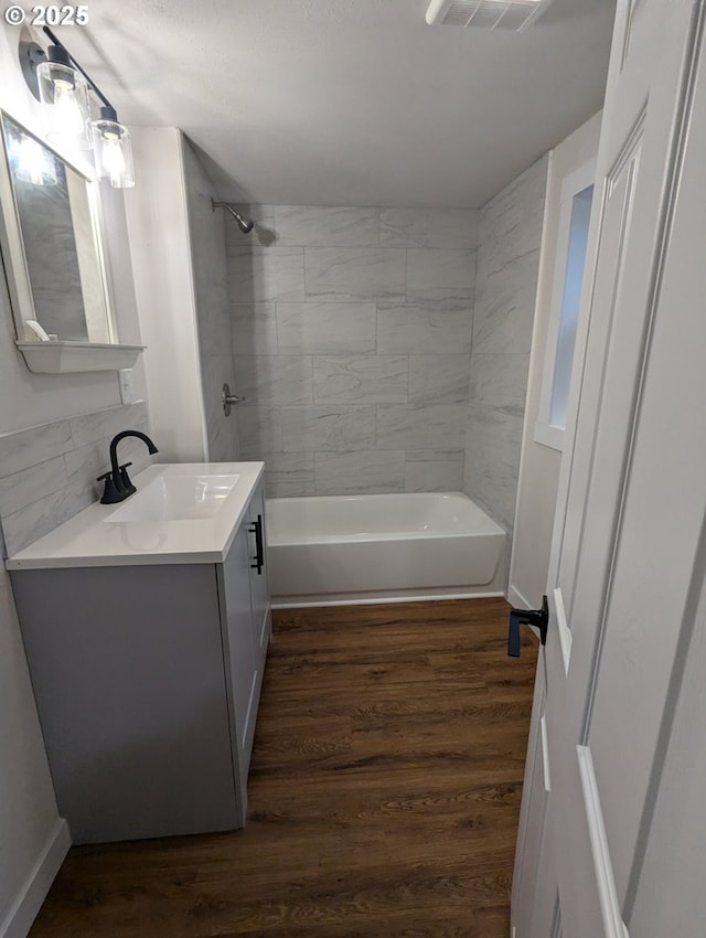 bathroom with tiled shower / bath combo, hardwood / wood-style flooring, and vanity