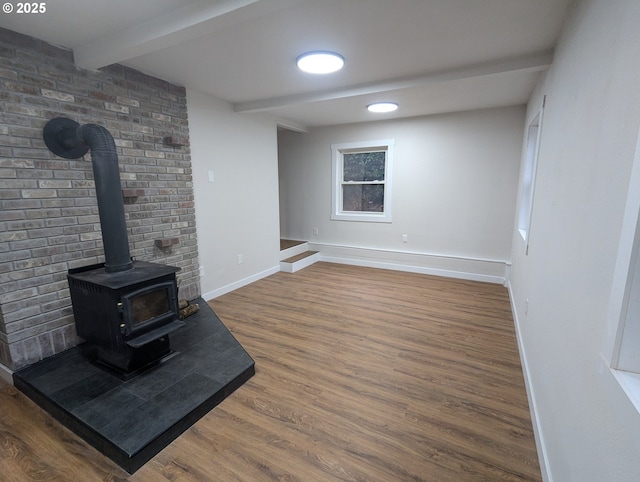 living room with dark wood-type flooring, a wood stove, and beamed ceiling