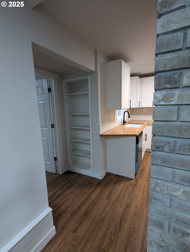 kitchen with wooden counters, built in shelves, sink, dark wood-type flooring, and white cabinets