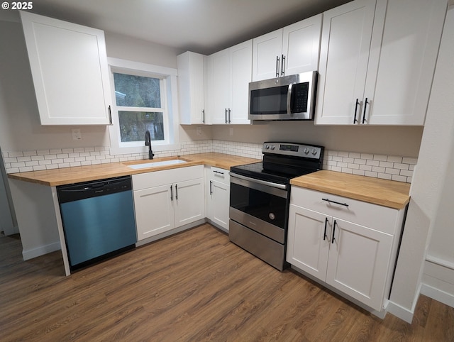 kitchen featuring dark hardwood / wood-style floors, sink, stainless steel appliances, white cabinets, and wood counters