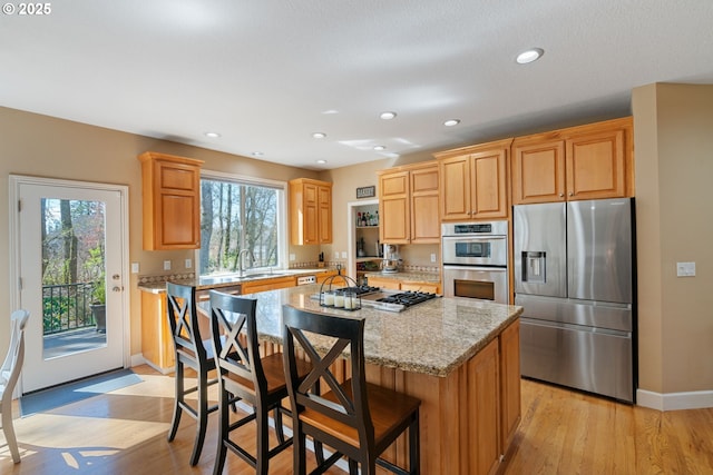 kitchen with a center island, a healthy amount of sunlight, light stone countertops, and stainless steel appliances