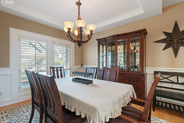 dining room featuring a tray ceiling, wood finished floors, and an inviting chandelier