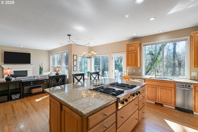 5666 Grand Oaks Dr, Lake Oswego, OR 97035 - kitchen featuring stainless steel gas cooktop, a sink, a center island, light wood-type flooring, and a chandelier
