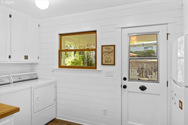 washroom featuring cabinet space, separate washer and dryer, and wood walls