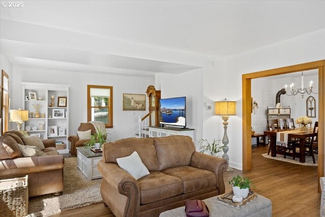 living room with a chandelier, wood finished floors, and stairs