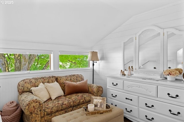 sitting room with vaulted ceiling and wood walls
