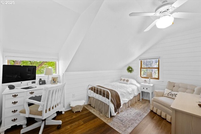bedroom with lofted ceiling, dark wood-type flooring, wood walls, a ceiling fan, and a desk