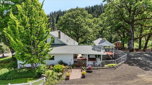 view of front of property with roof with shingles and a view of trees