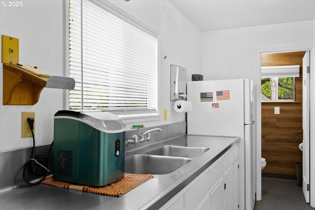 kitchen with a sink, white cabinetry, and freestanding refrigerator