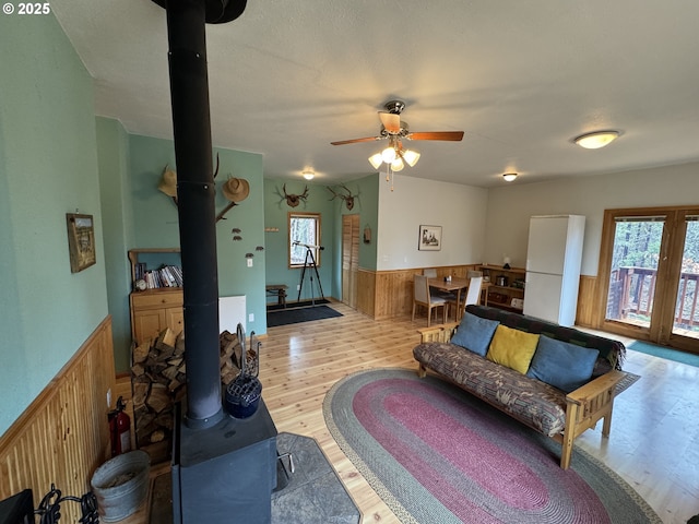 118 Noble Fir, Goldendale, WA 98620 - living area with a wood stove, wainscoting, plenty of natural light, wood finished floors, and wooden walls