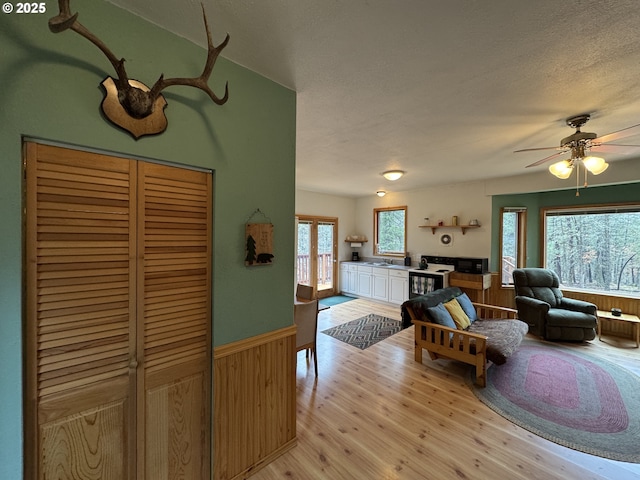 118 Noble Fir, Goldendale, WA 98620 - living area with light wood-style flooring, wainscoting, a textured ceiling, ceiling fan, and wood walls