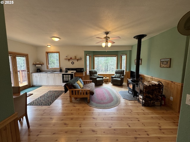 118 Noble Fir, Goldendale, WA 98620 - living area featuring a wood stove, healthy amount of natural light, wainscoting, a ceiling fan, and light wood finished floors