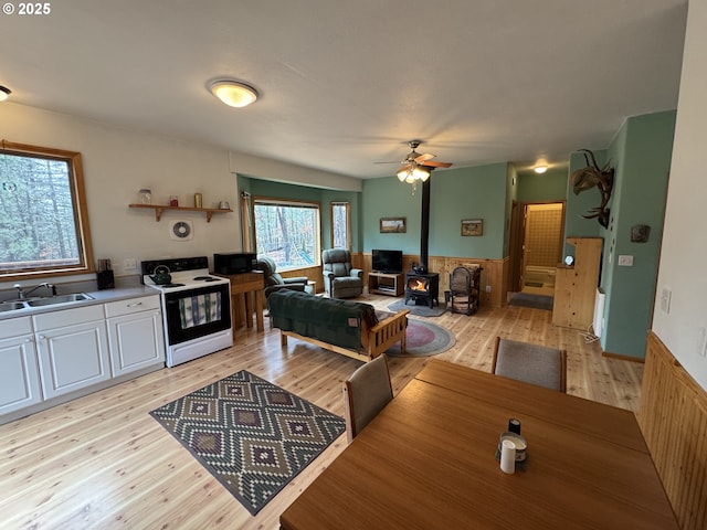 118 Noble Fir, Goldendale, WA 98620 - living area featuring a wood stove, a wainscoted wall, light wood finished floors, and a ceiling fan