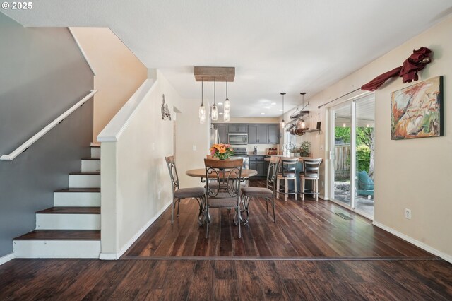 dining room featuring stairs, baseboards, and wood finished floors