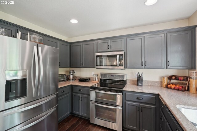 kitchen with recessed lighting, dark wood-style floors, gray cabinetry, and stainless steel appliances