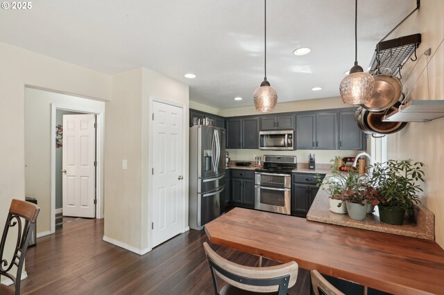 kitchen with baseboards, recessed lighting, light countertops, dark wood finished floors, and appliances with stainless steel finishes