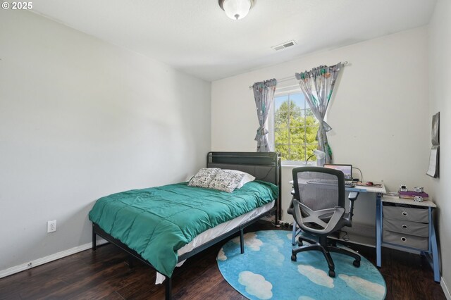 bedroom featuring baseboards, wood finished floors, and visible vents
