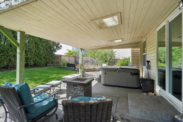 view of patio / terrace with a fenced backyard, a hot tub, and an outdoor fire pit