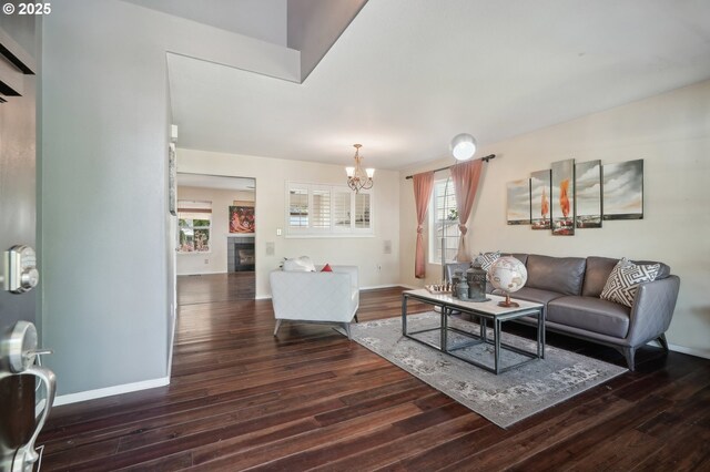 living area featuring baseboards, wood finished floors, a chandelier, and a fireplace