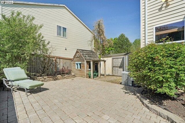 view of patio / terrace with central air condition unit, fence, an outbuilding, and a storage unit