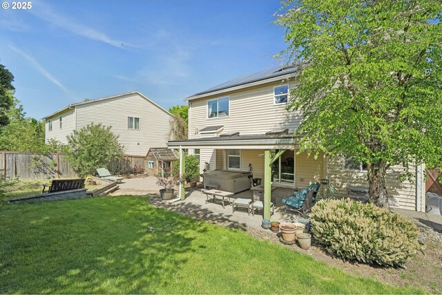 back of house with a hot tub, a patio, a fenced backyard, and a lawn