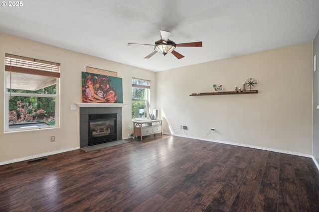 unfurnished living room featuring visible vents, a ceiling fan, wood finished floors, and a tiled fireplace